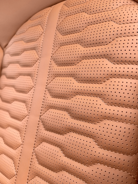Detail van cognackleurige autobekleding met patroon en stiksels